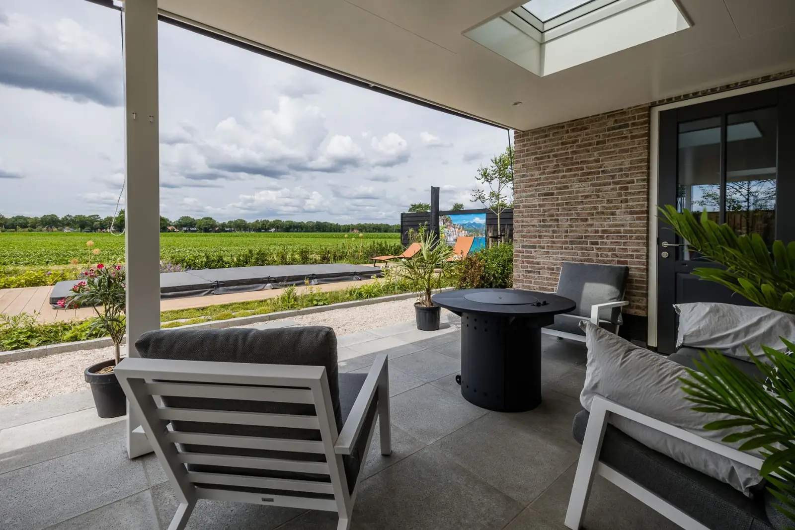 Zicht vanuit de overkapping met loungeset op de jacuzzi en het weiland in Hardenberg