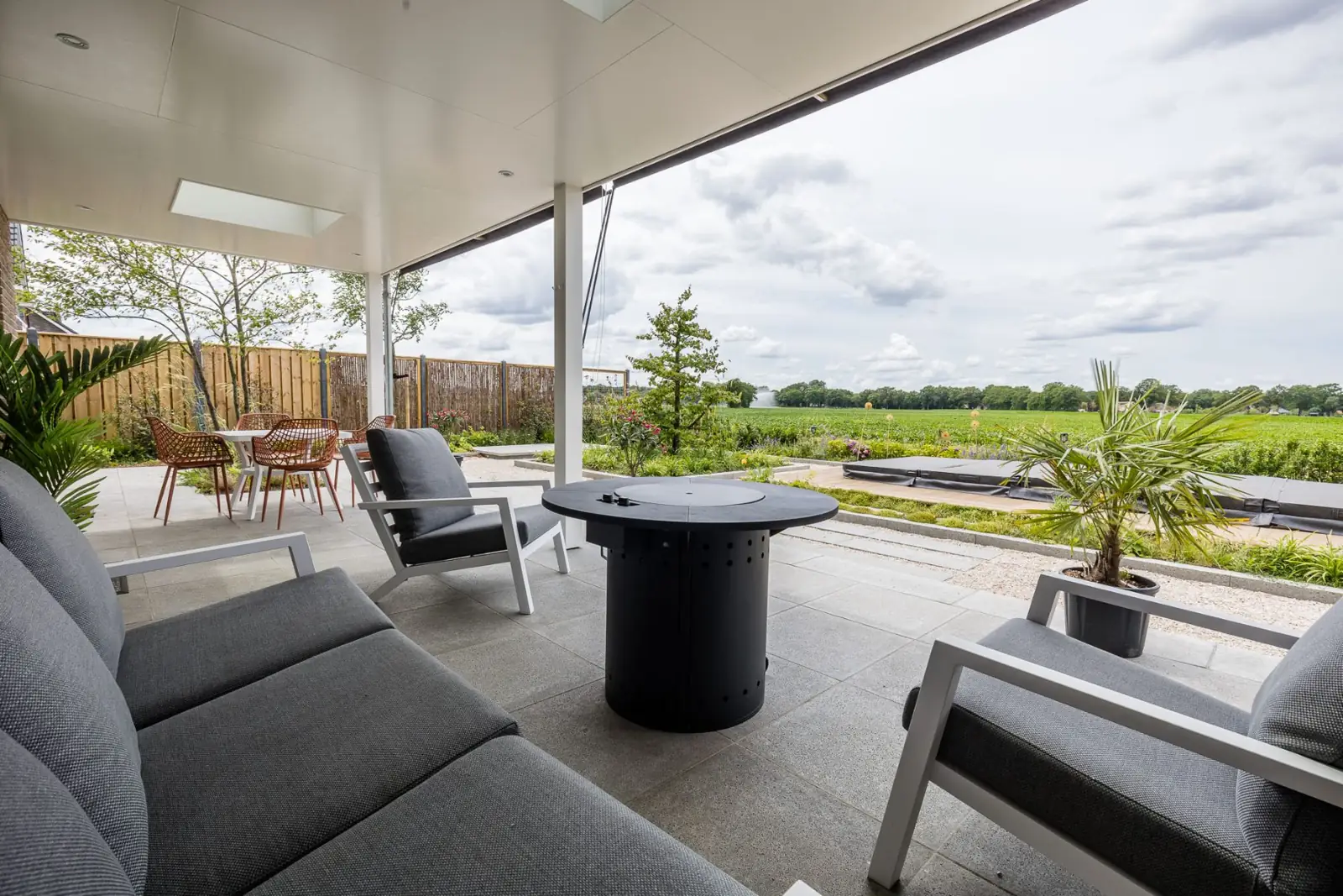 Overkapping met loungeset en vuurtafel met zicht op tuin en weiland in Hardenberg