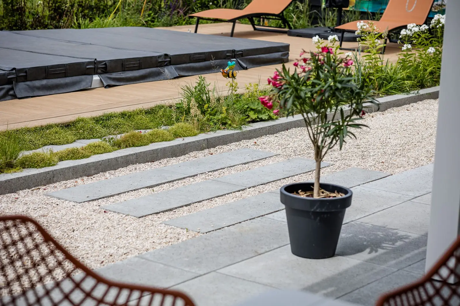 Betonnen stapstroken in grind met zicht op jacuzzi en ligbedden in Hardenberg