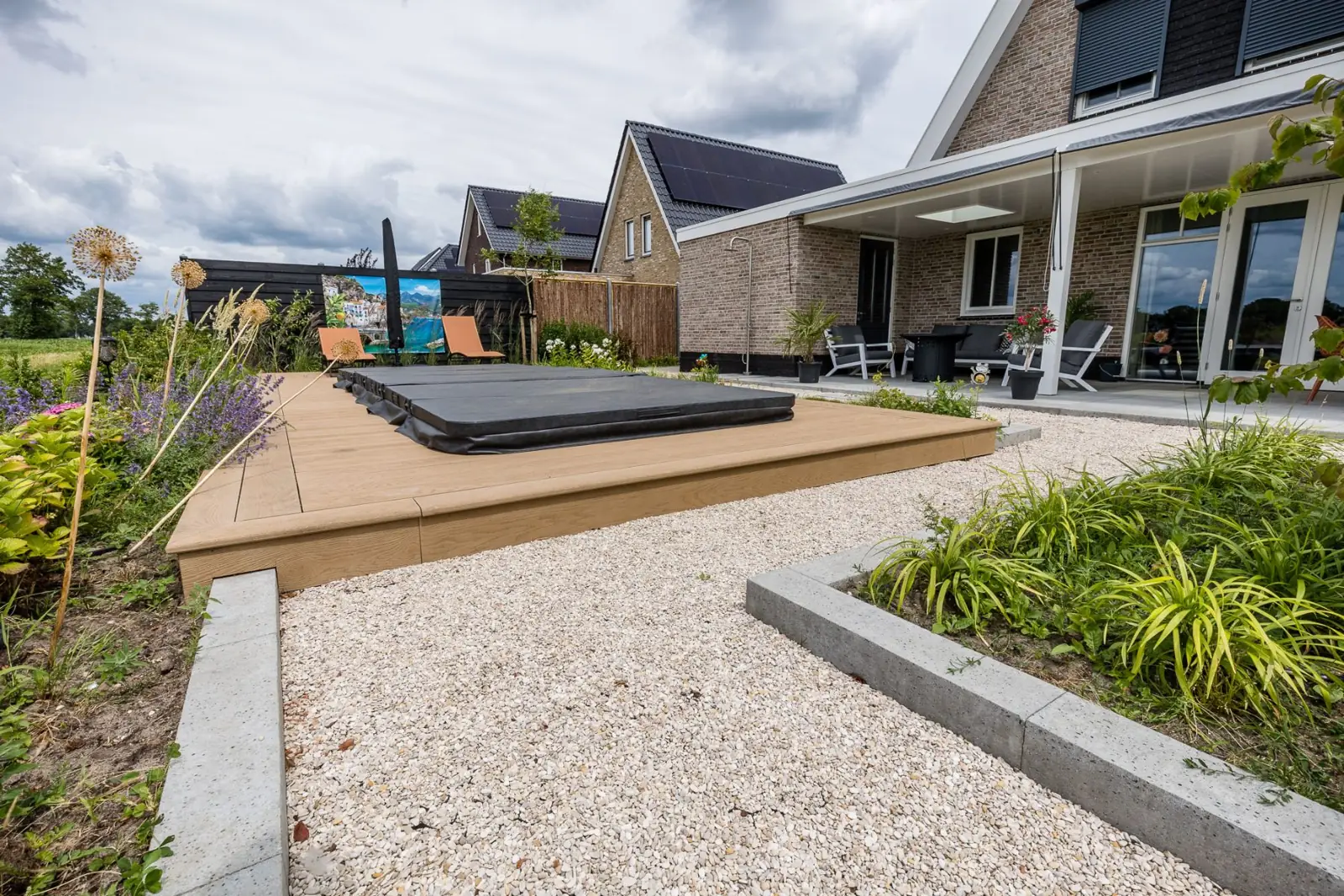 Composietvlonder met jacuzzi aan een grindpad met betonnen opsluitbanden in Hardenberg