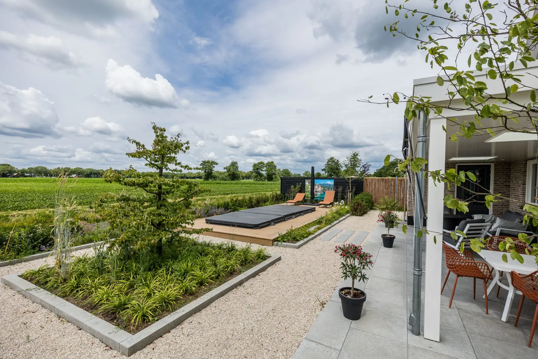 Wellnesstuin in Hardenberg met jacuzzi op een composietvlonder, overkapping en zicht op het weiland