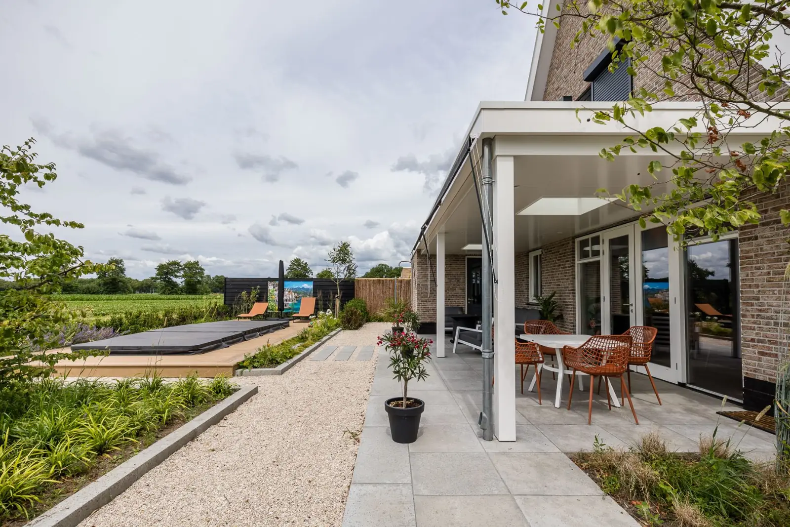 Terras onder de overkapping langs het grindpad naar de jacuzzi in Hardenberg