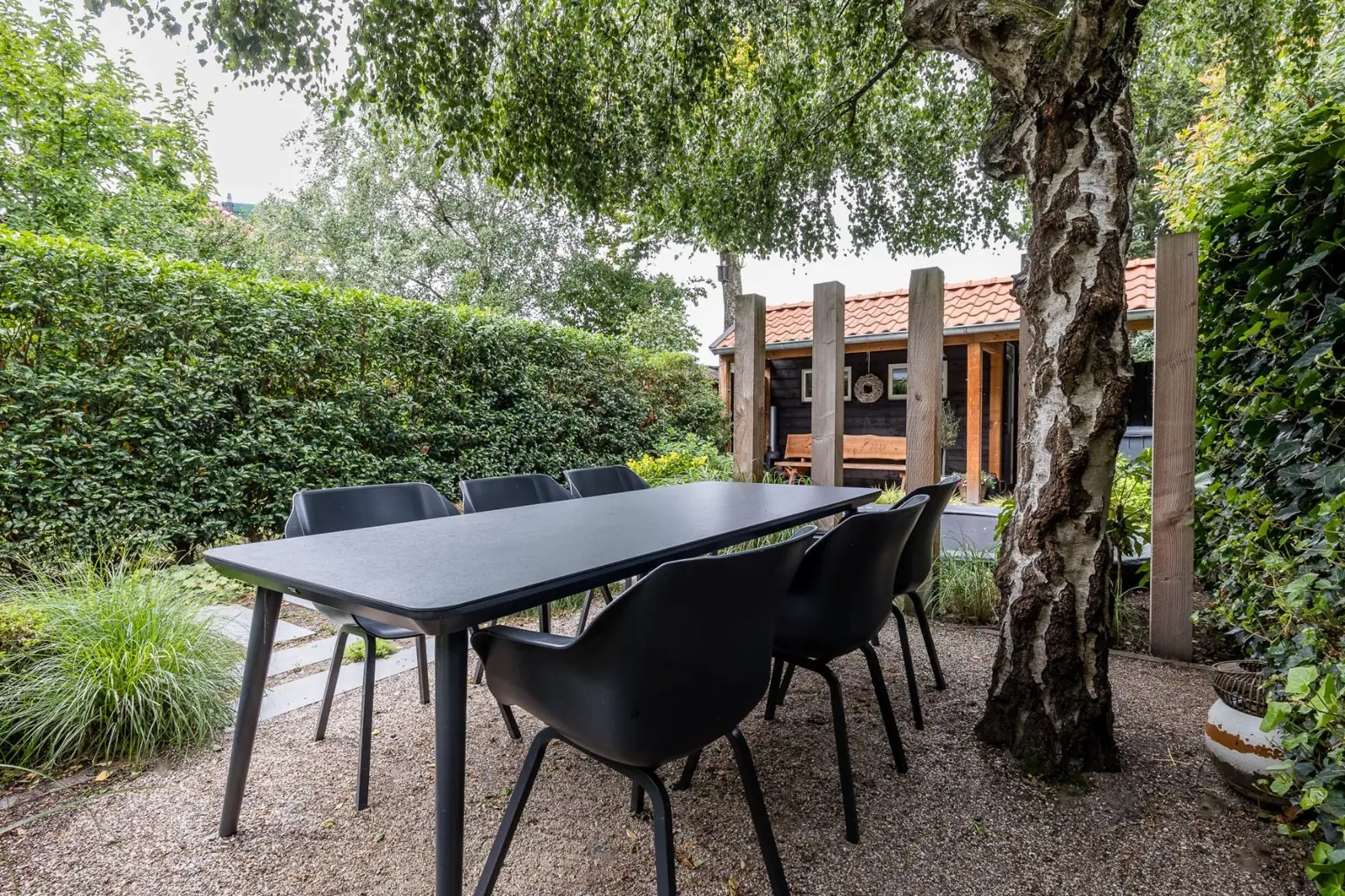 Eettafel onder de treurberk met zicht op de houten overkapping in Zwolle