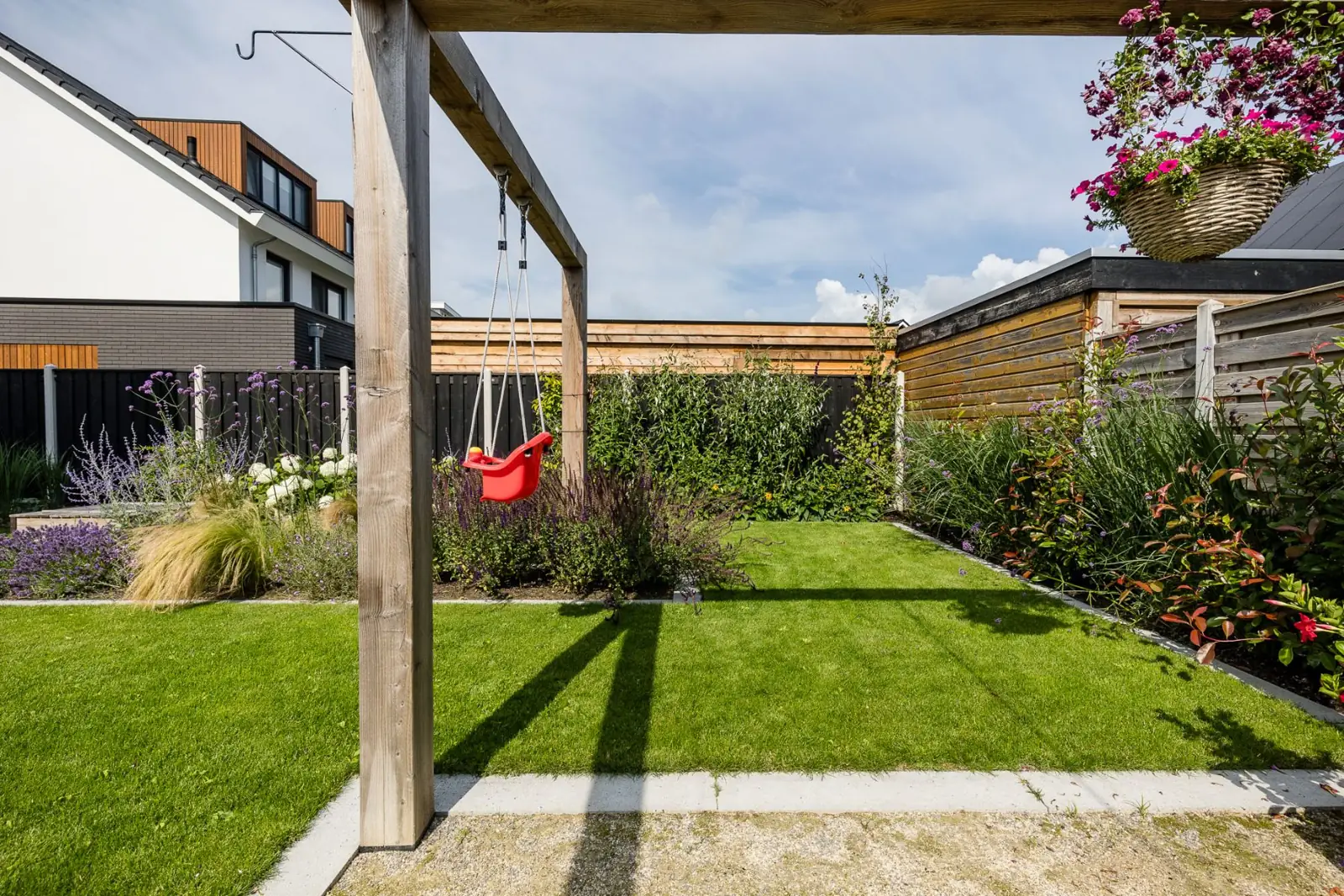 Houten pergola met kinderschommel boven het gazon in een gezinstuin in Lemelerveld
