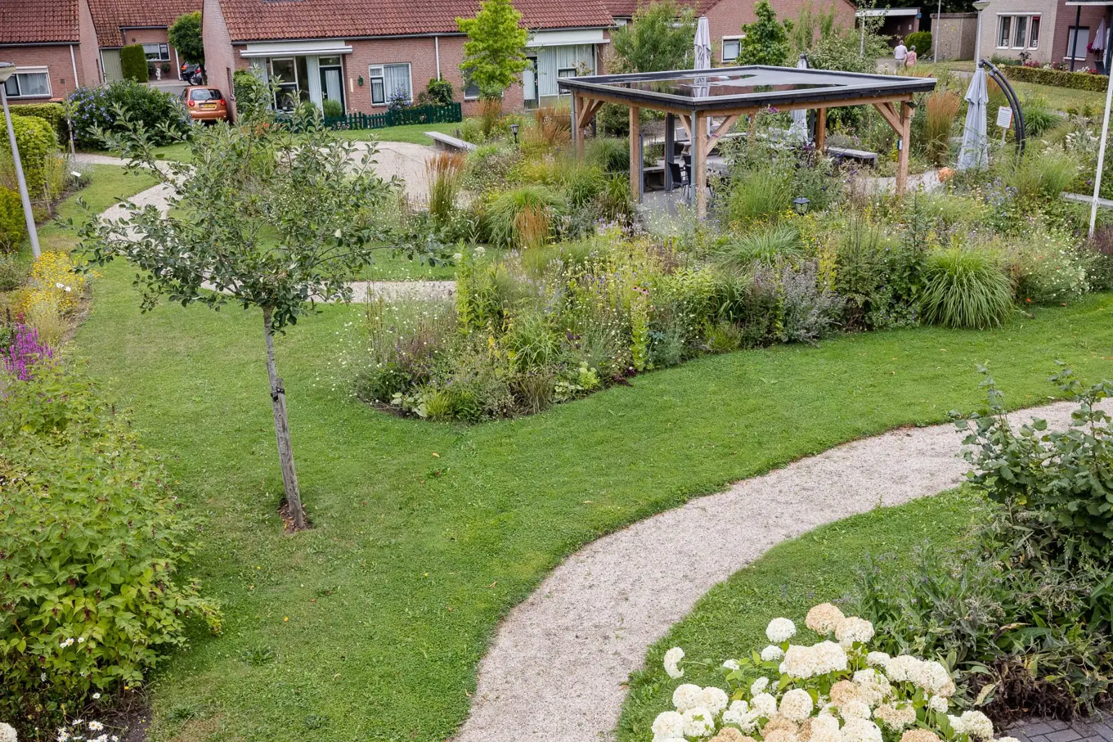 Binnentuin gazon grindpad overkapping borders in Raalte