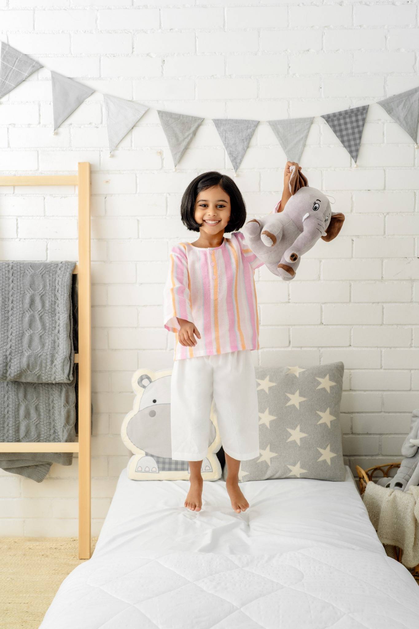 A child standing on a white bed with star cushions