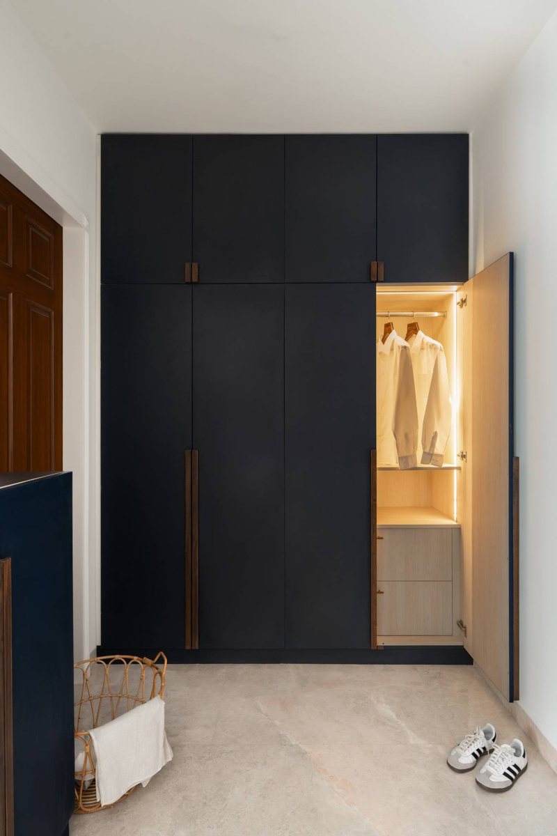 A navy built-in wardrobe with a lit open section in a teen's room