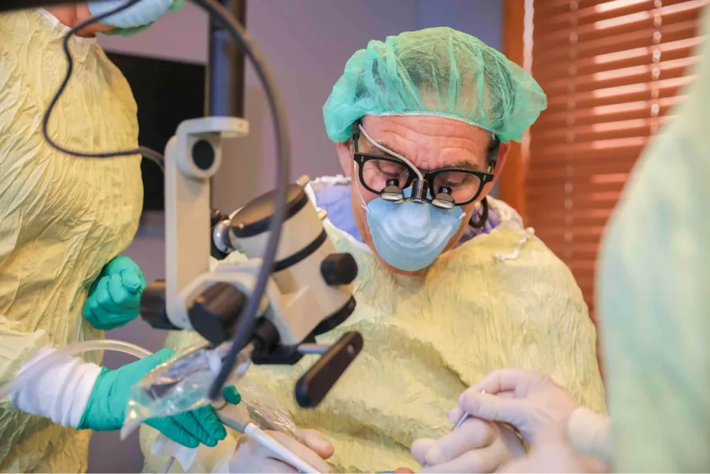 Surgeon placing a dental implant under a microscope