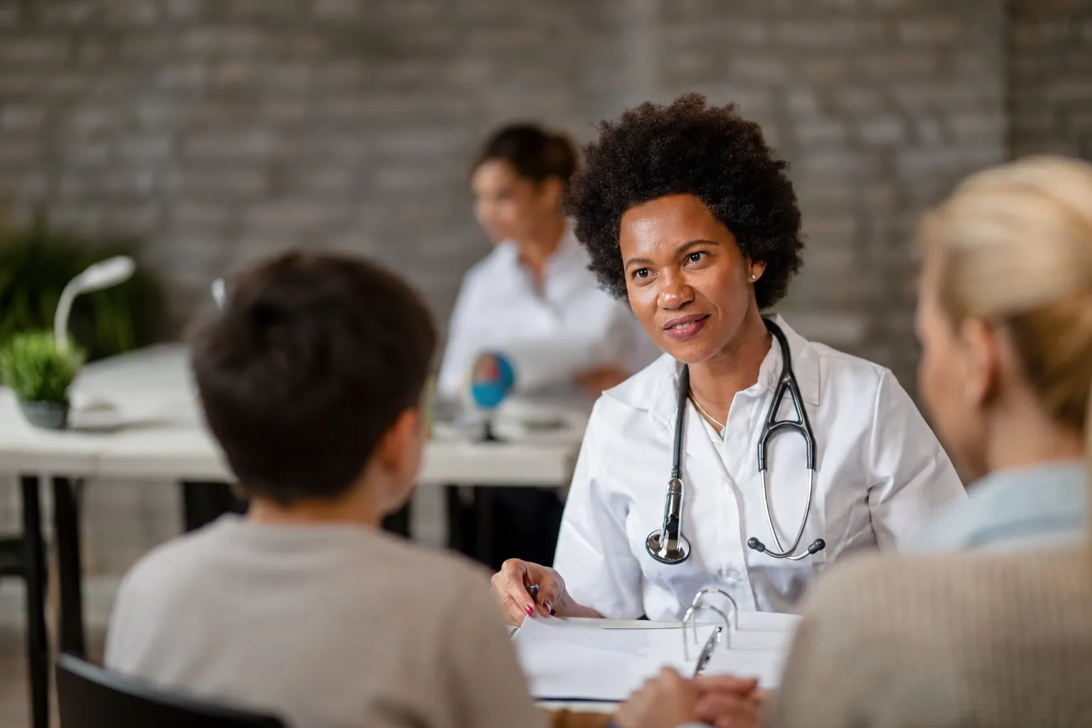 Physician speaking with a young patient and parent during a well-child visit