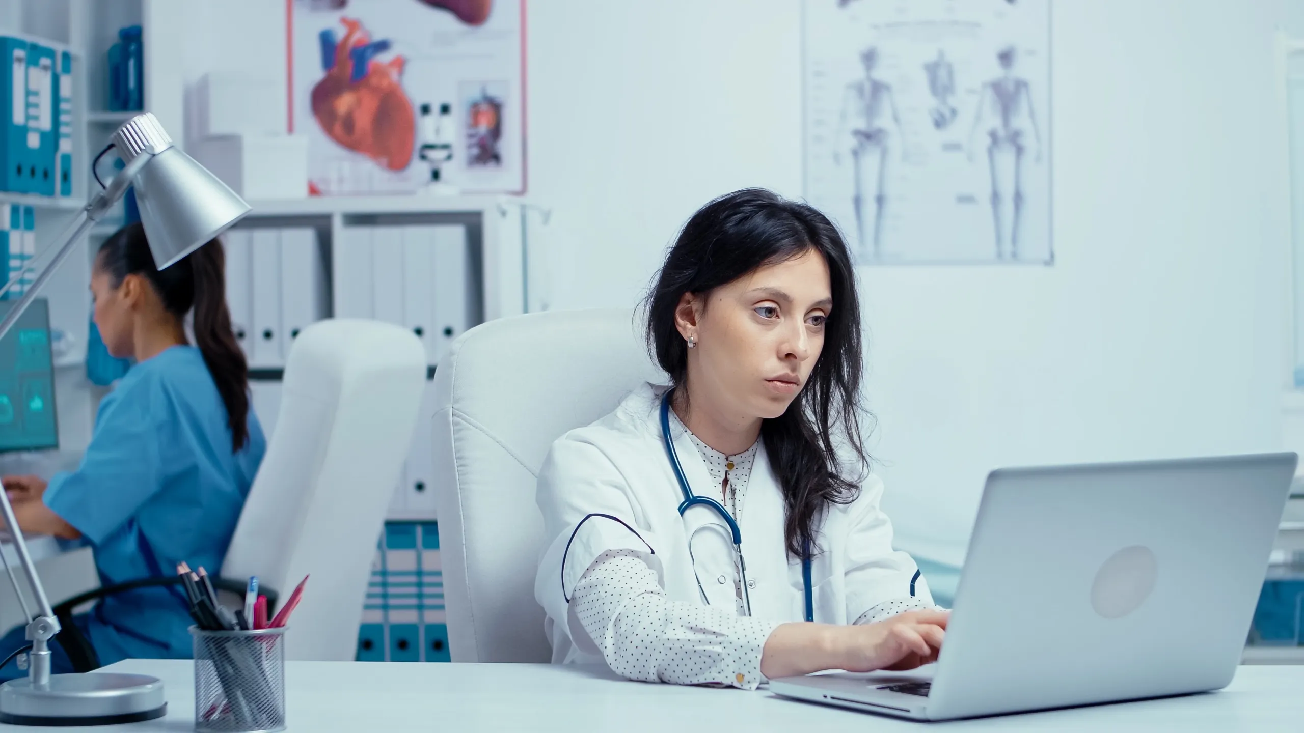 Physician reviewing patient records on a laptop in a clinic office
