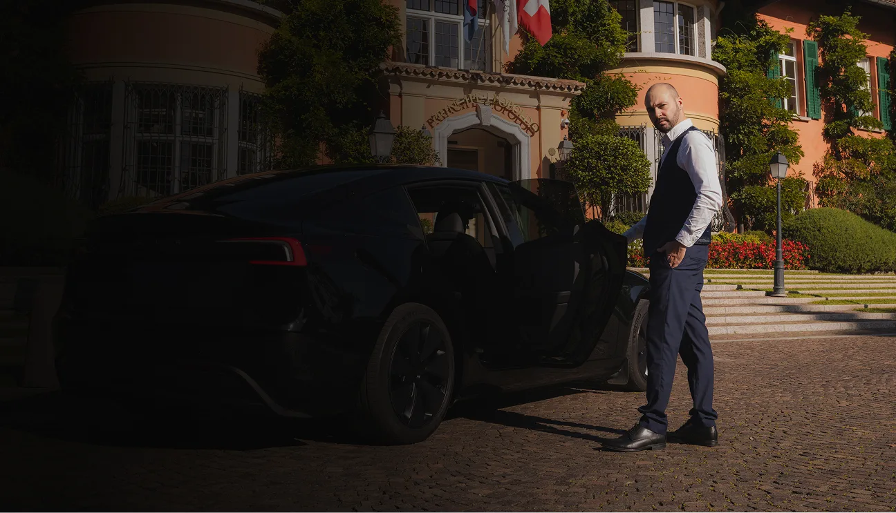 Autista privato apre portiera Tesla Model 3 nera davanti a hotel in Ticino