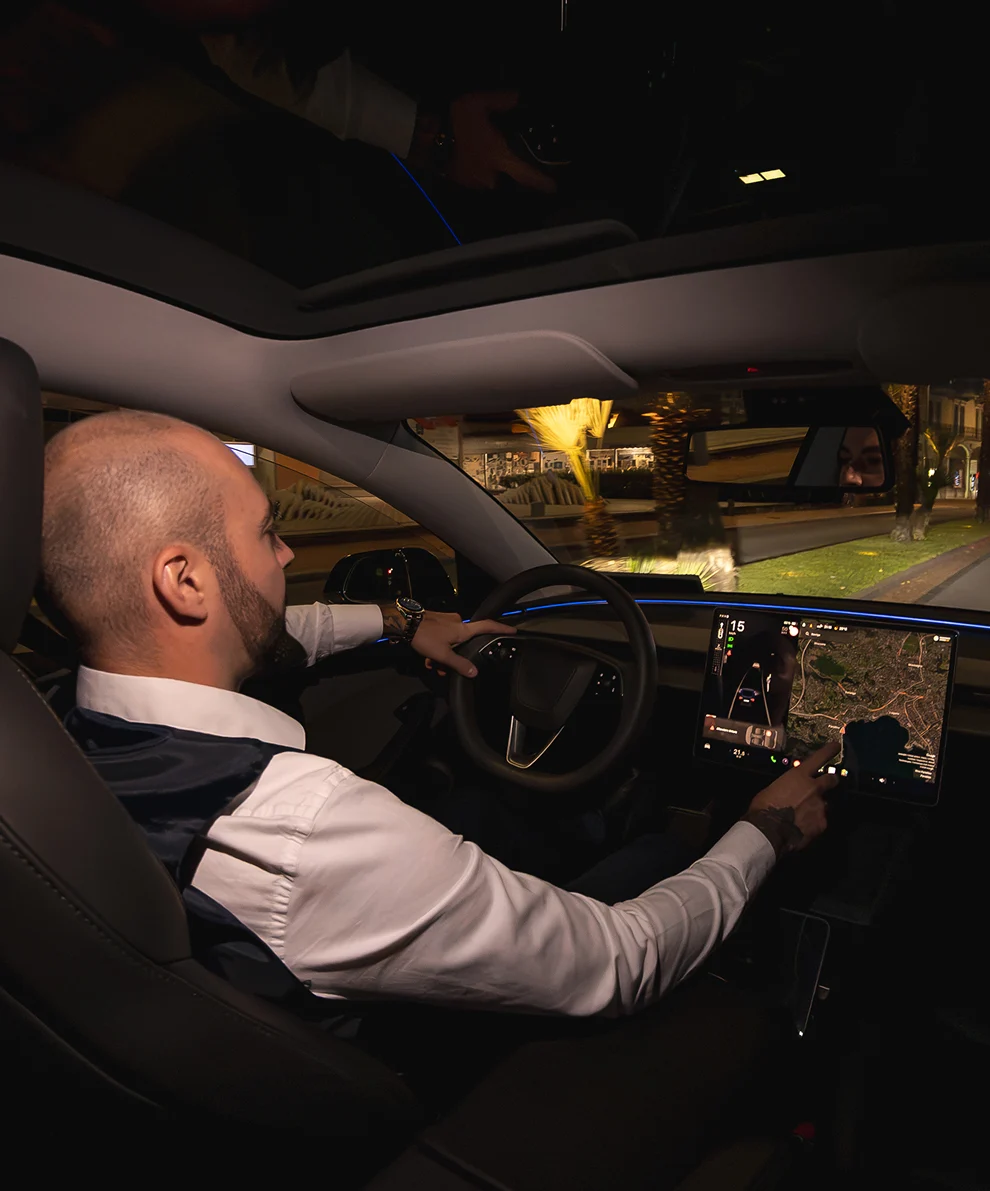 Autista taxi Tesla al volante di notte a Lugano con navigatore