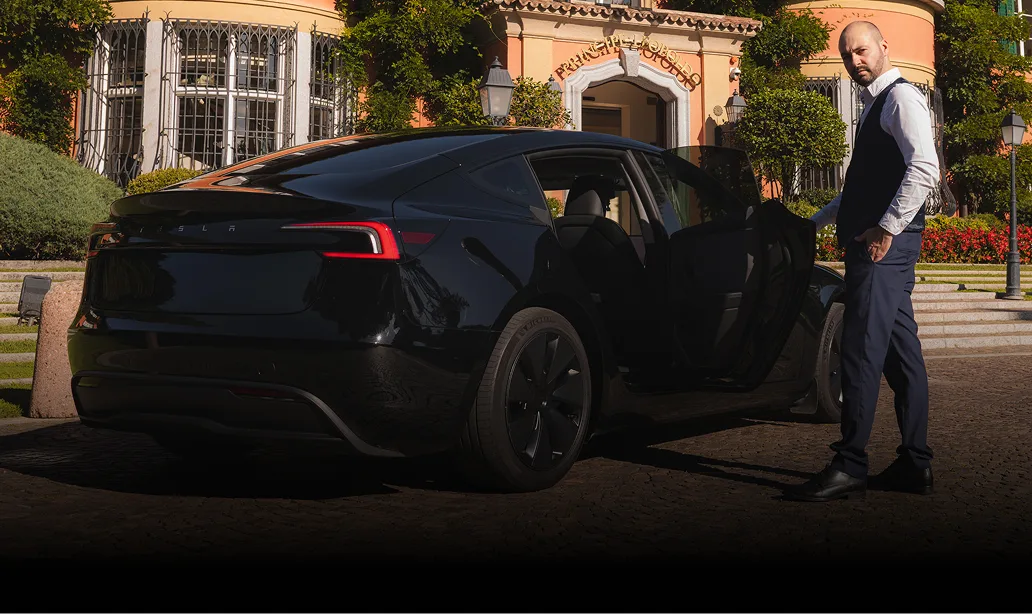 Autista privato apre portiera Tesla Model 3 nera davanti a hotel in Ticino