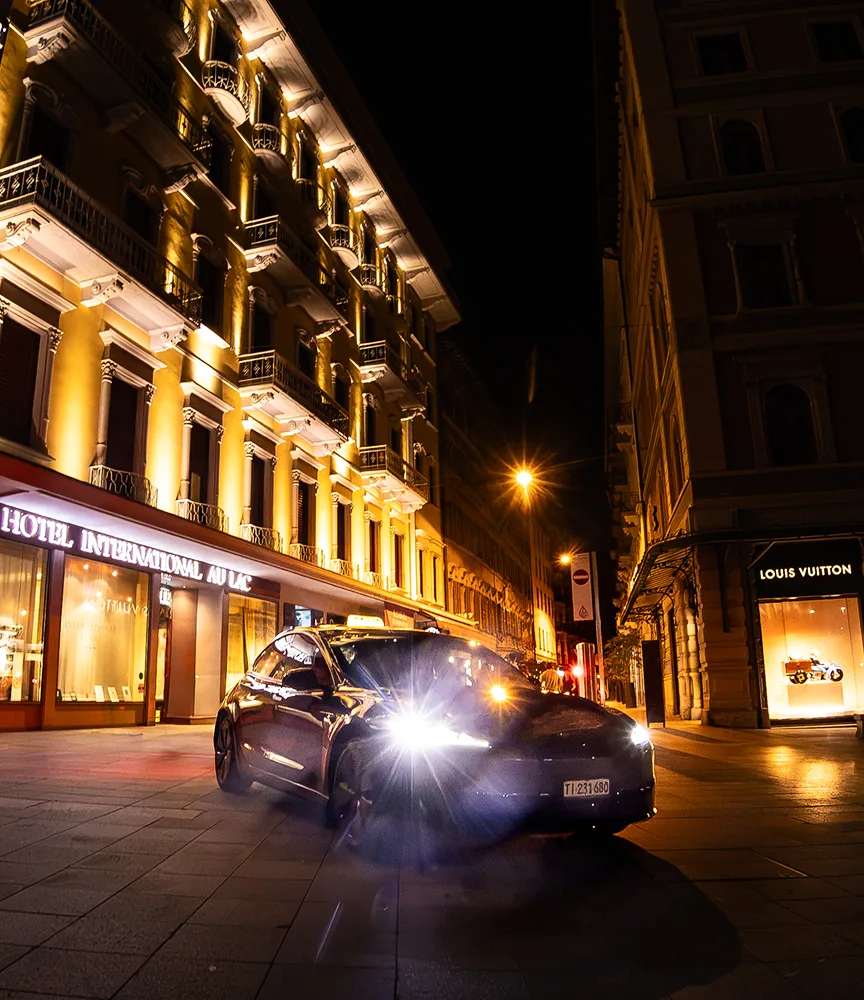 Tesla taxi notturno davanti a un hotel nel centro di Lugano