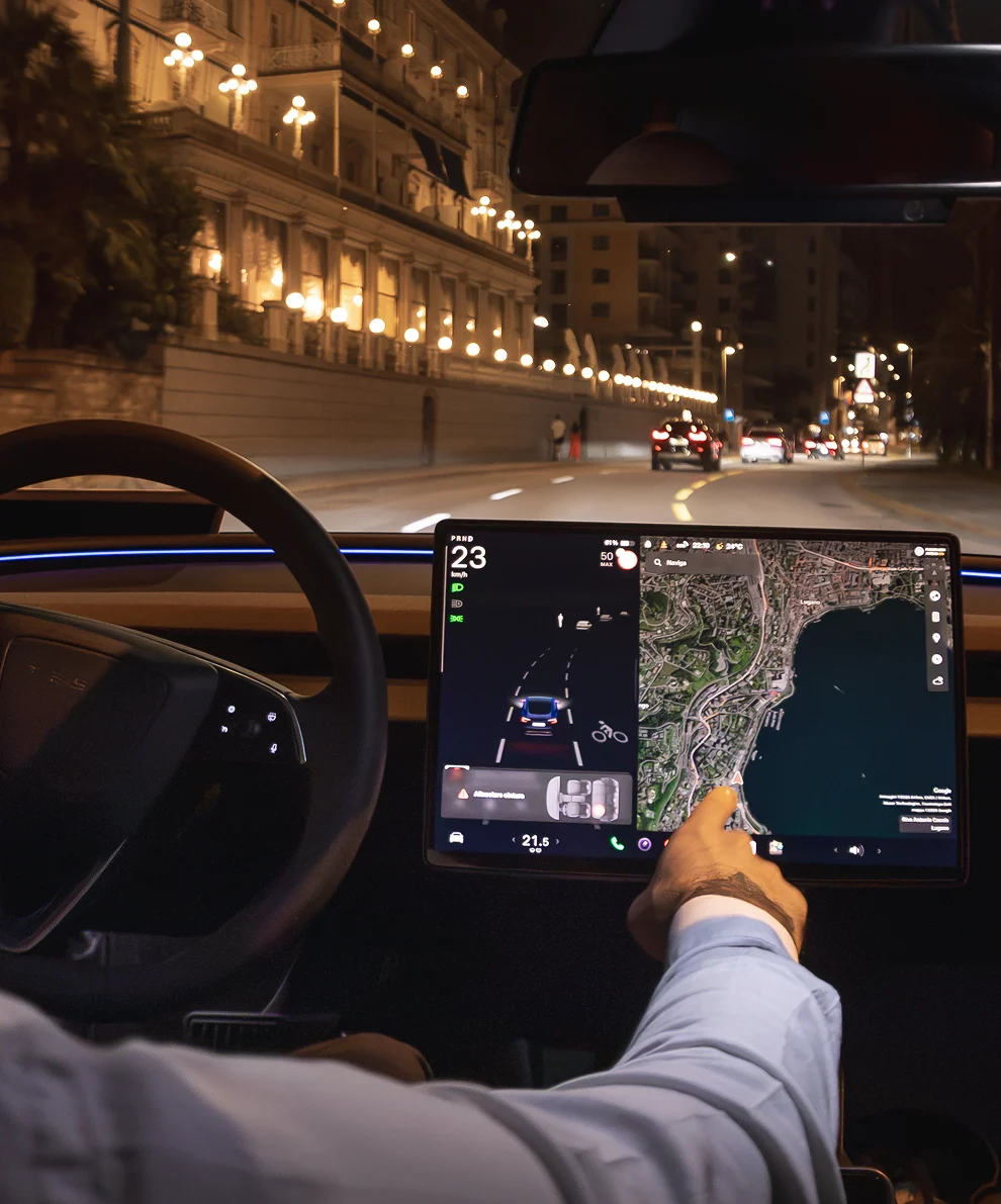 Autista taxi Tesla al volante di notte a Lugano con display navigazione