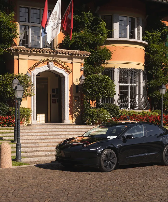 Taxi Tesla Model 3 nera davanti a hotel di lusso in Ticino