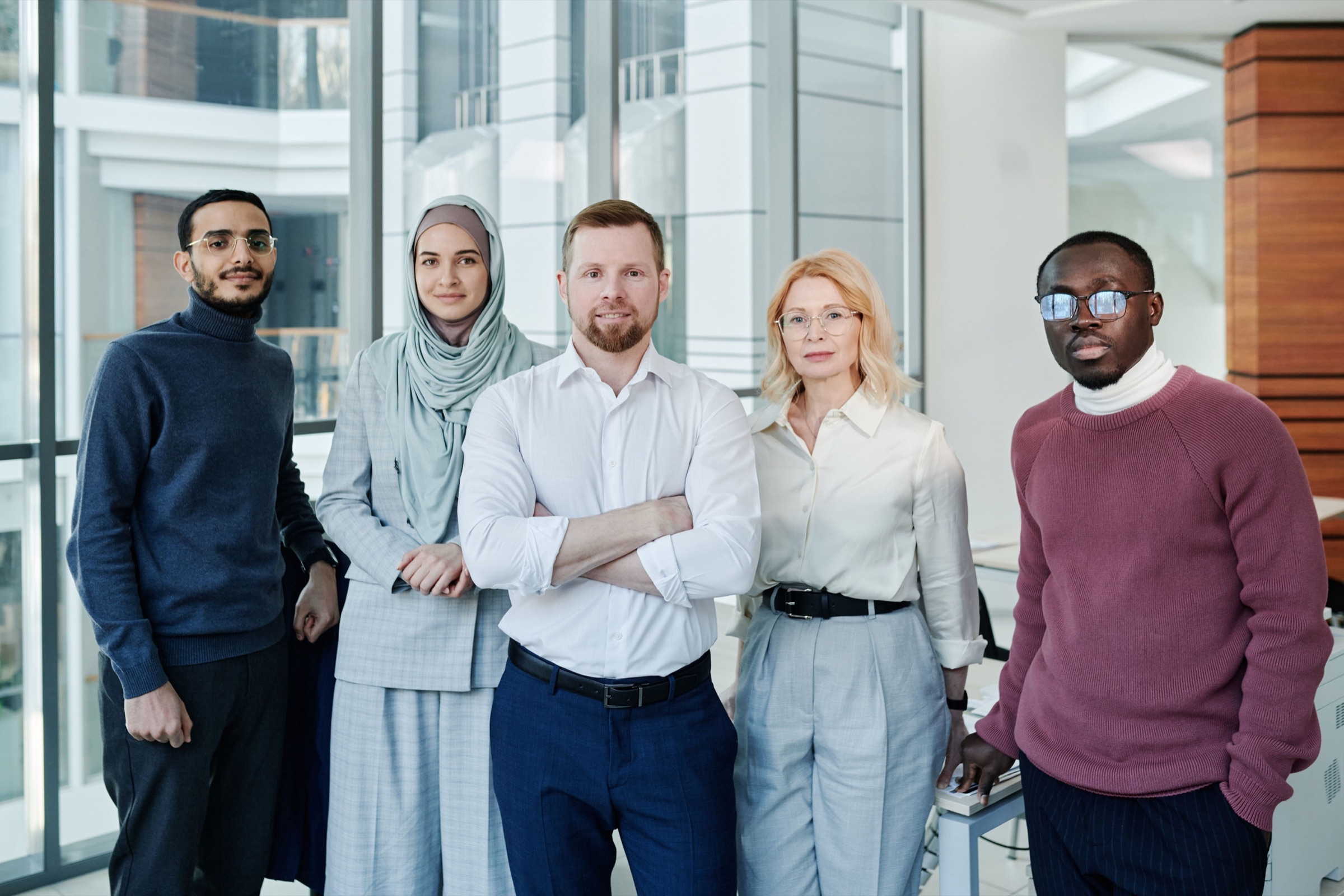 Five colleagues standing together in an office.