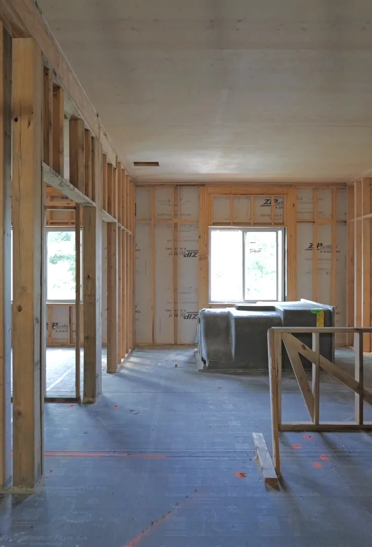 A long top-floor space with wood stud framing and a window at the far end.