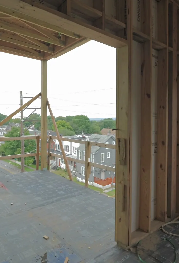 An open framed corner on the top floor, looking out over neighborhood rooftops and trees.