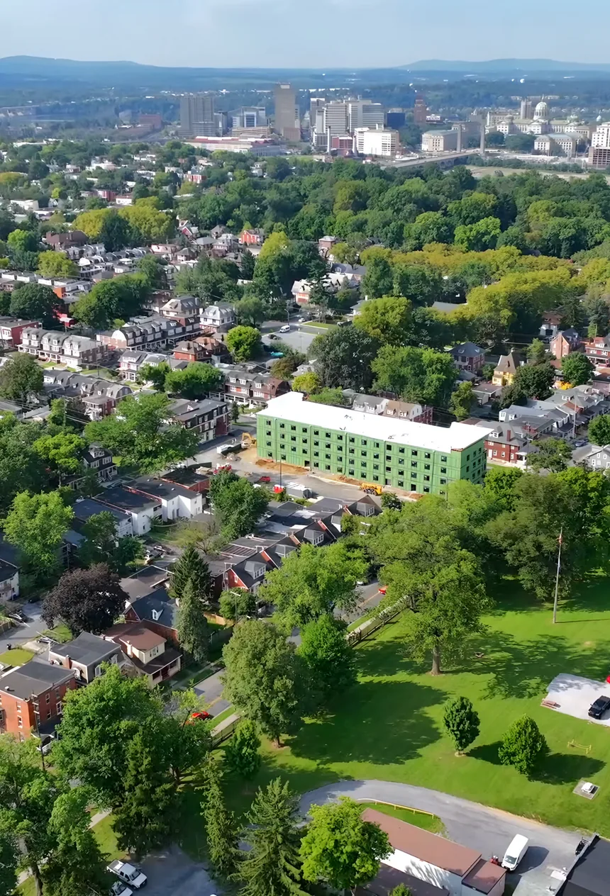 Wide aerial view over Harrisburg with downtown in the distance, and Woodward Lofts and the brick armory in the foreground.
