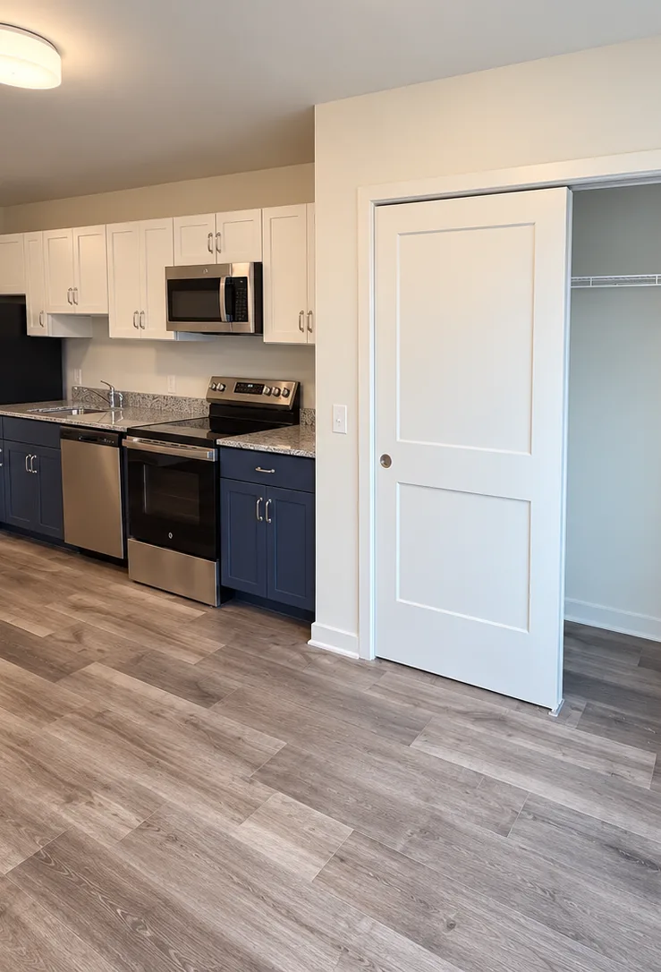 A studio kitchen and an open closet next to a tall window.