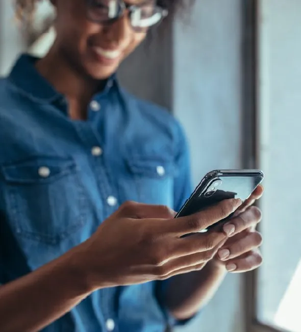 Smiling man in glasses texting on his smartphone