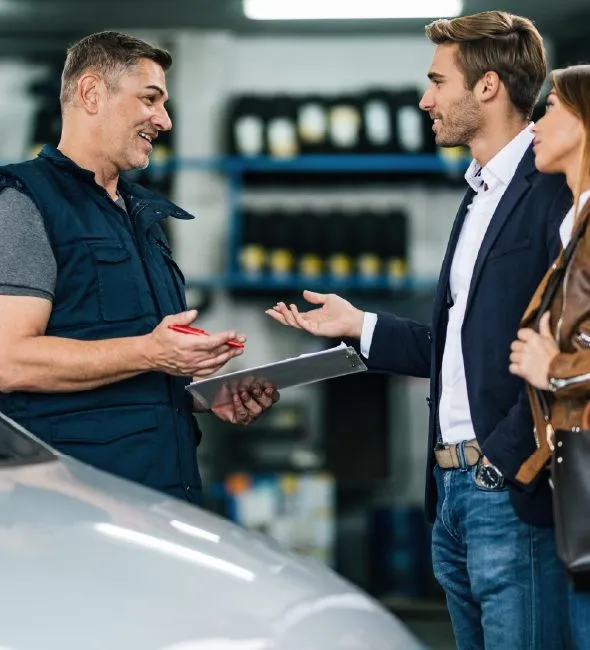 Mechanic talking with a couple in an auto repair shop
