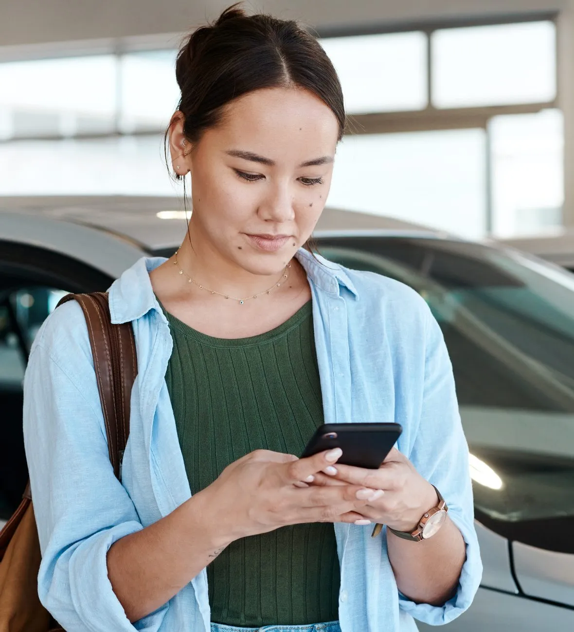 Woman checking her phone in a car dealership showroom