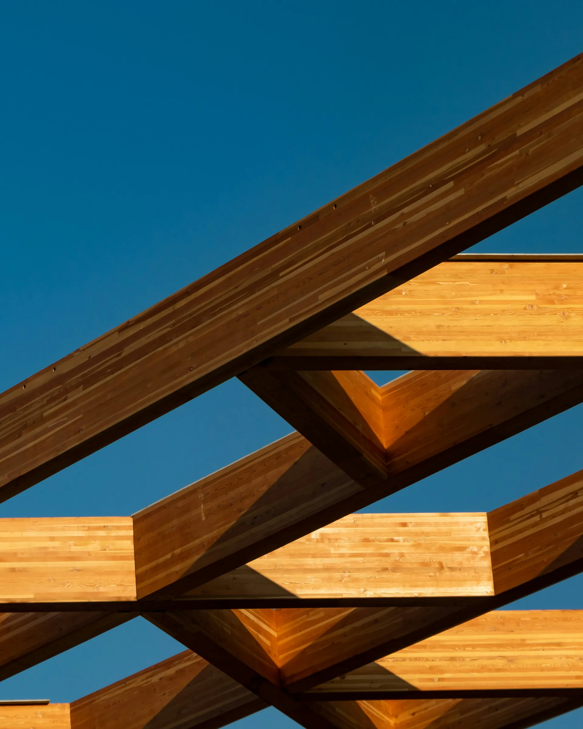 Warm timber beams crossing against a deep blue sky.
