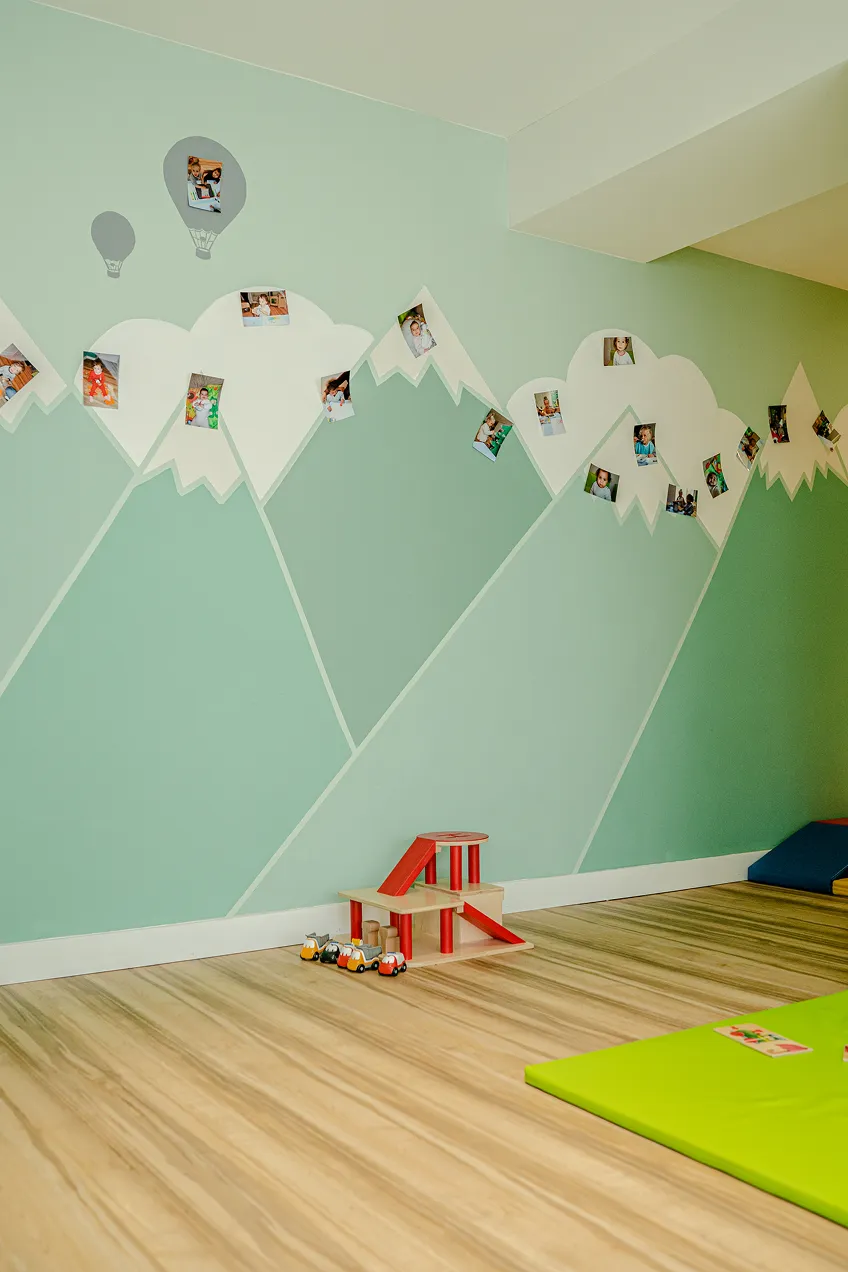 Salle d'activité avec des montagnes peintes au mur et les photos des enfants