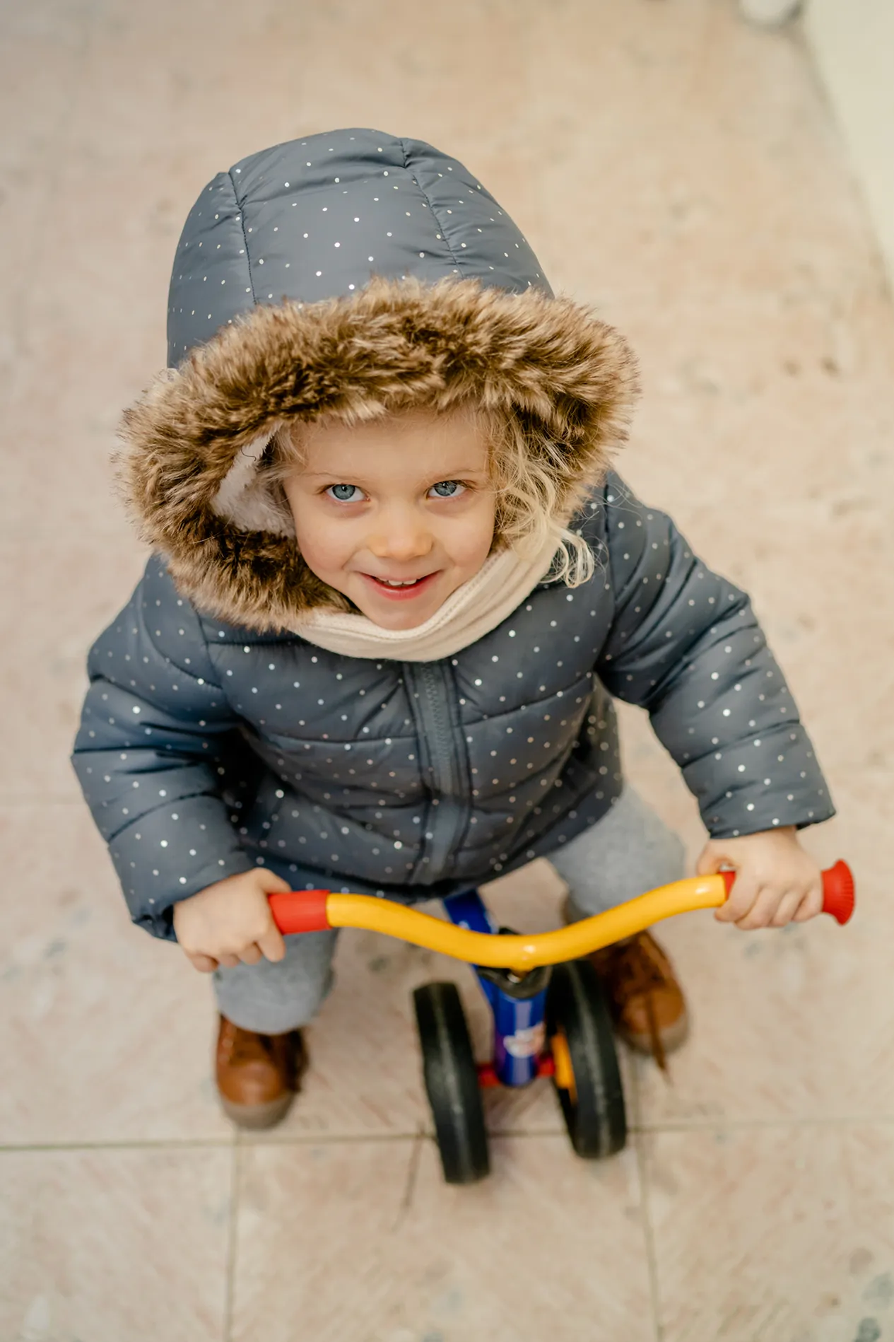 Un enfant souriant sur un tricycle dans la crèche