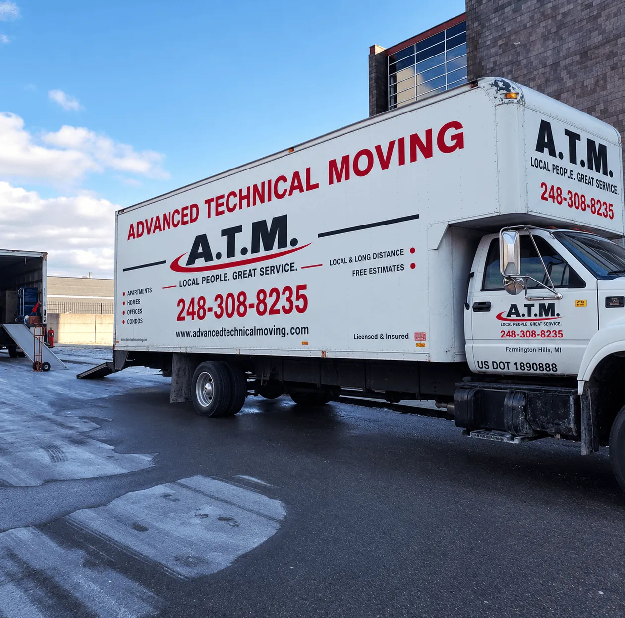 Advanced Technical Moving truck parked outside a commercial building with the loading ramp down