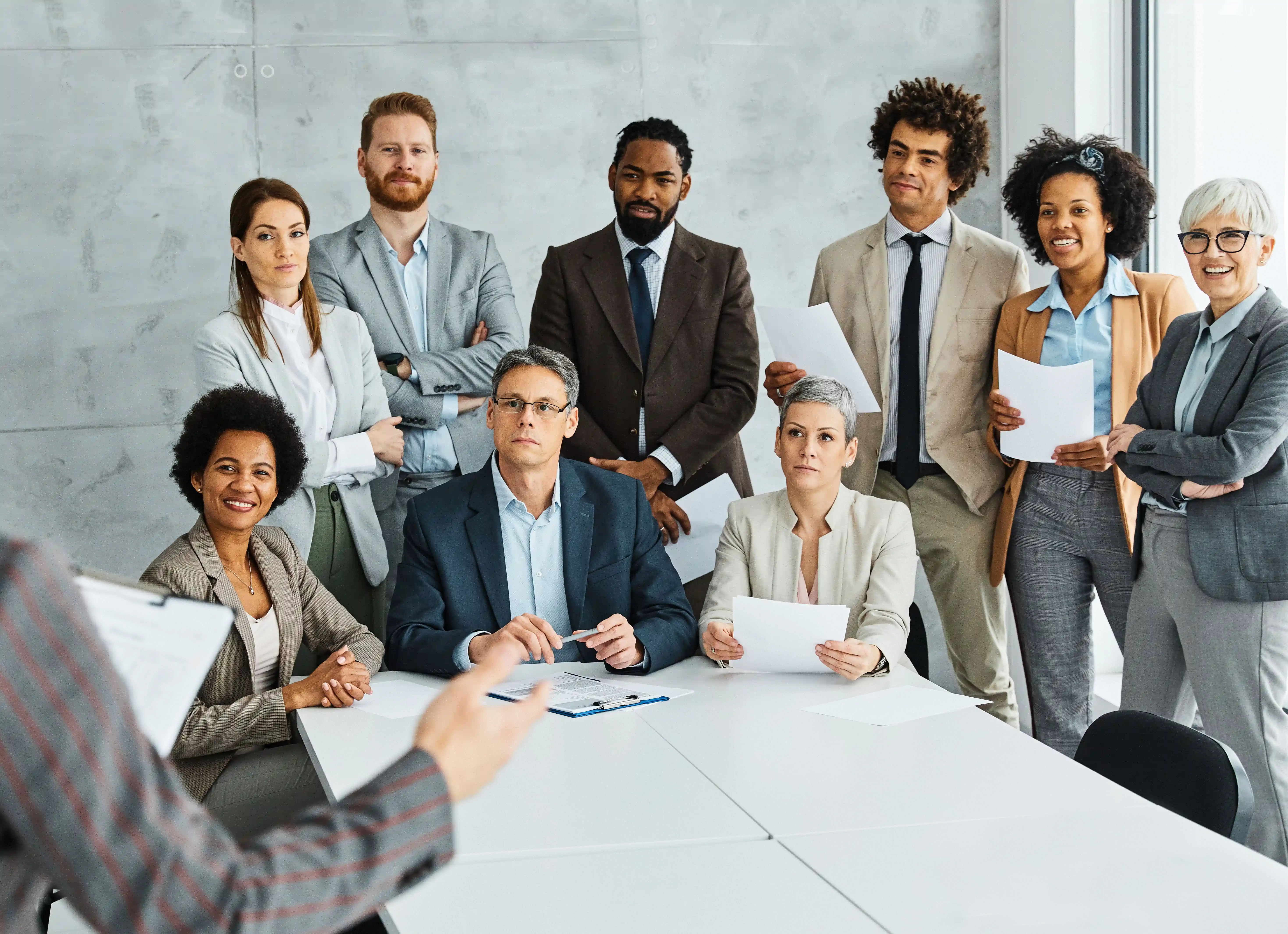 Diverse business team attentively listening to a presenter during a meeting in a modern office.