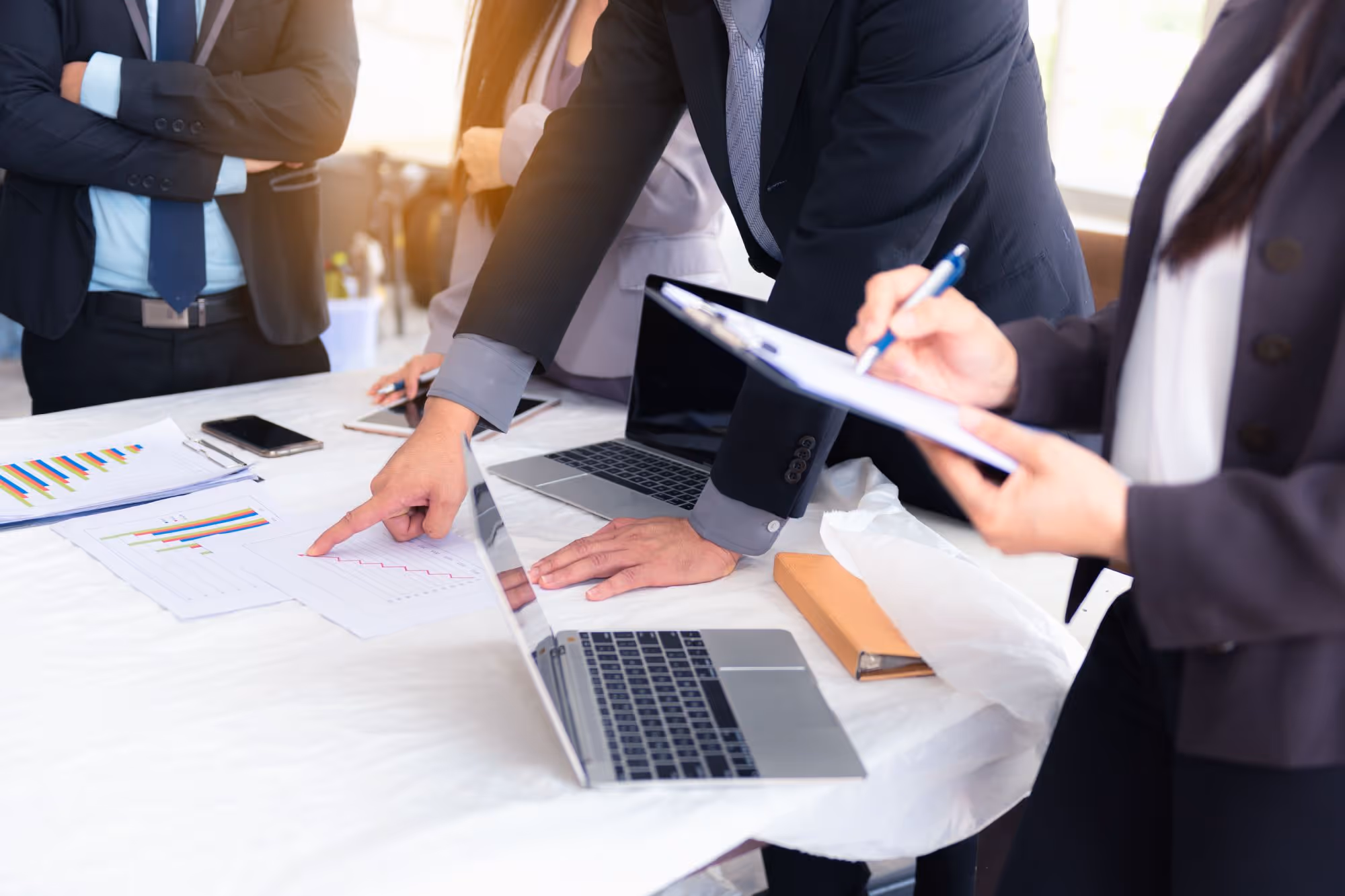 Business professionals reviewing financial charts and data on paper and laptop at a meeting.