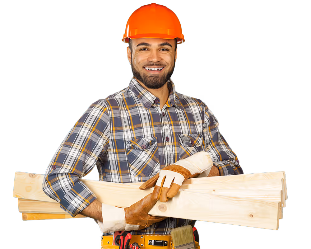 Smiling construction worker wearing an orange hard hat and gloves holding several wooden planks.