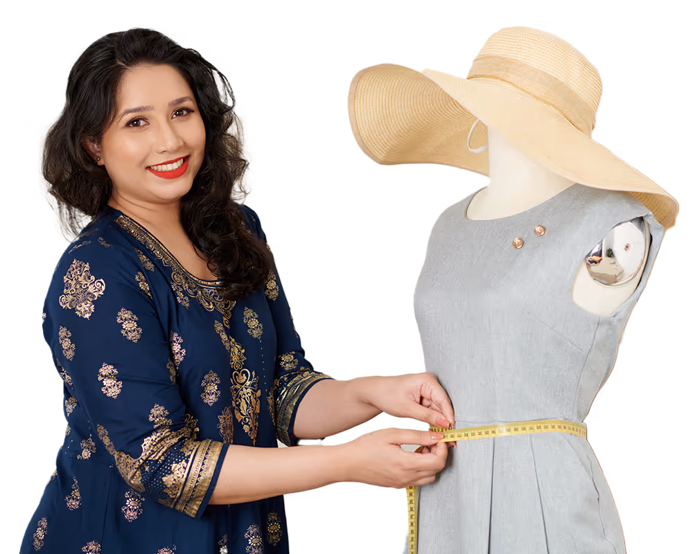 Woman in blue patterned dress measuring the waist of a dress form wearing a light gray dress and a wide-brimmed hat.