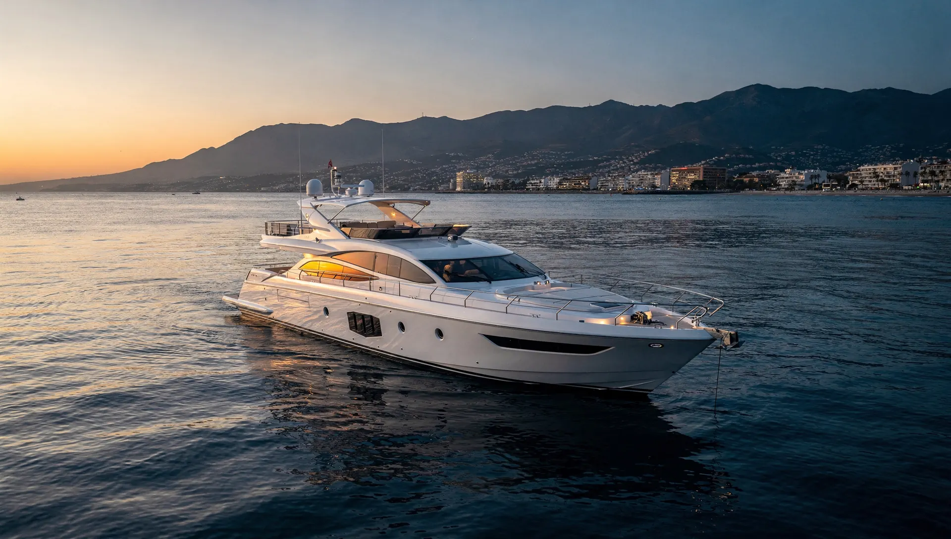A white motor yacht at anchor off the coast at sunset