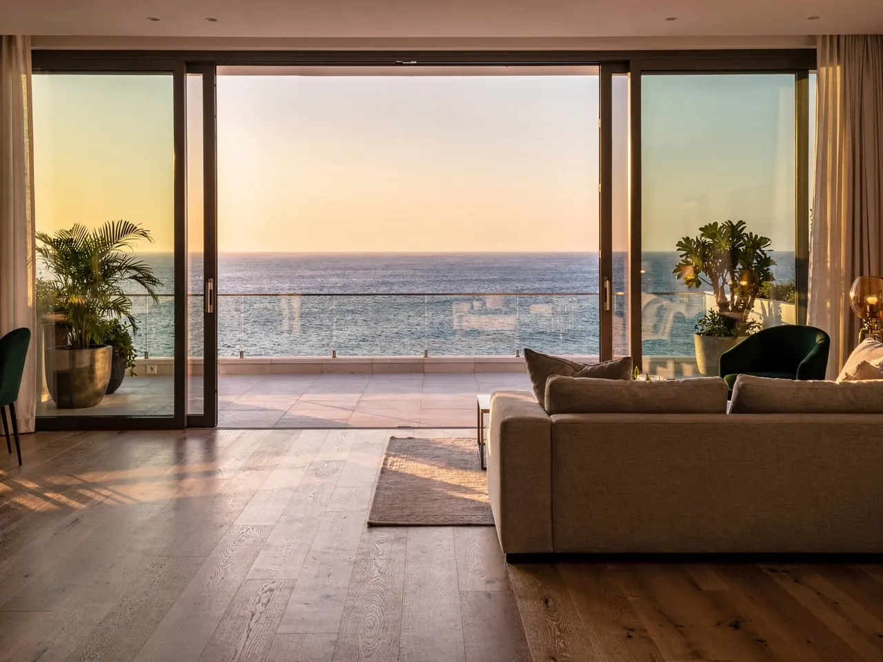 An apartment living room opening onto a terrace over the sea at sunset