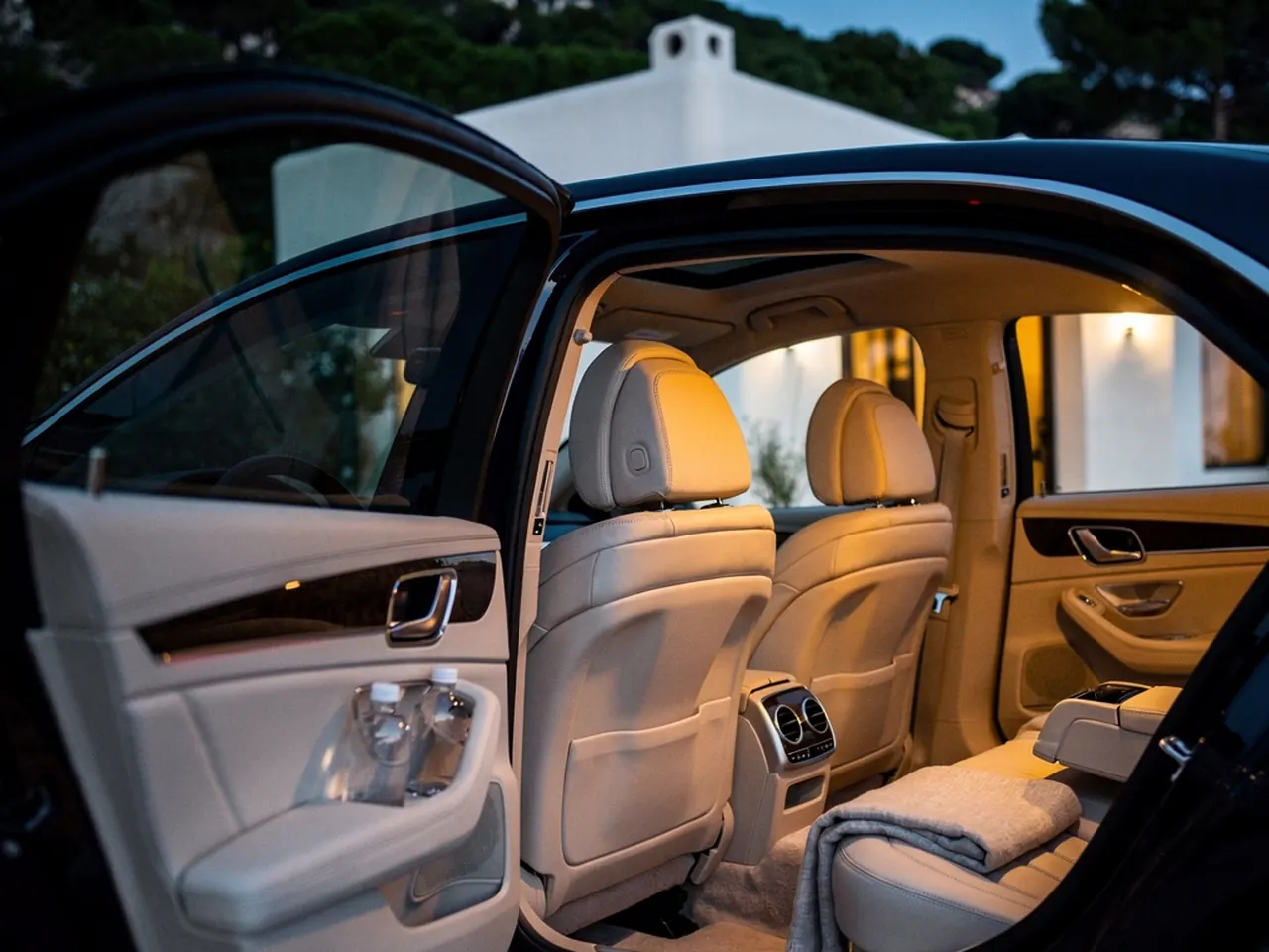 A dark saloon car waiting at a villa entrance at dusk