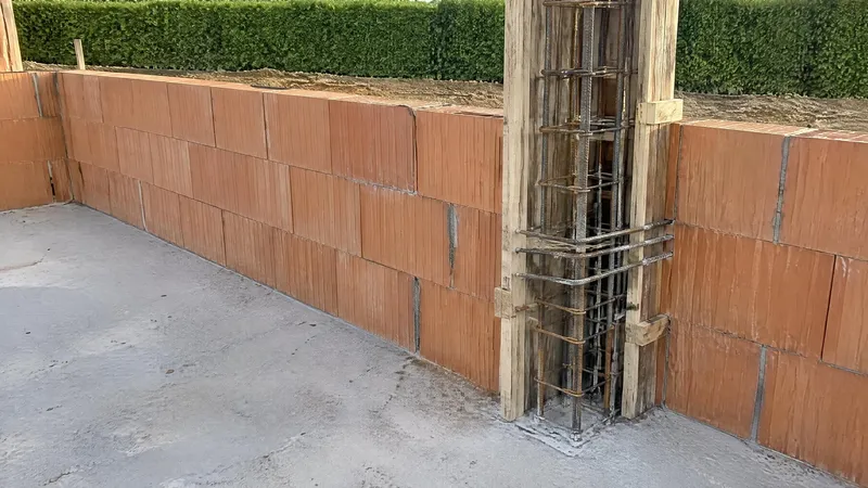 Angle d'un mur en briques : armatures verticales et cadres d'un chaînage dans leur coffrage
