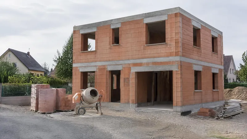 Maison individuelle en briques au stade du gros œuvre : rez-de-chaussée et étage montés, chaînages et linteaux béton, arase en tête, sans toiture