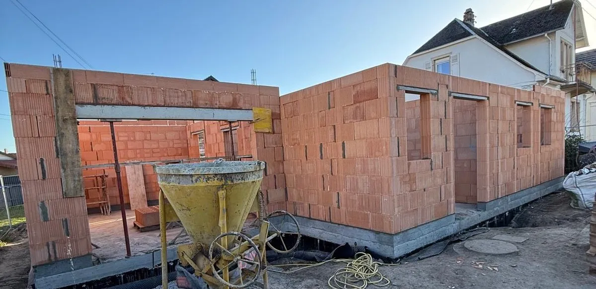 Murs de brique d'une maison de Haguenau en cours de construction, benne à béton au premier plan