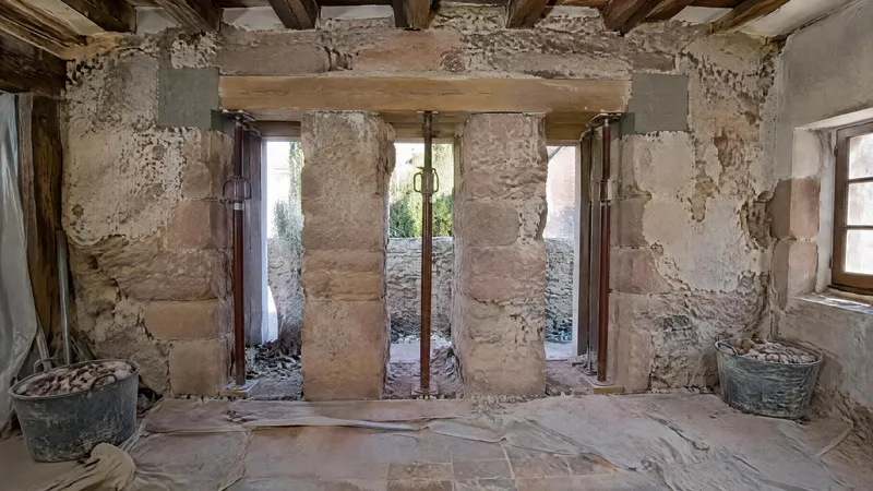Mur ancien en grès ouvert par passes alternées, étais et dés d'appui en béton