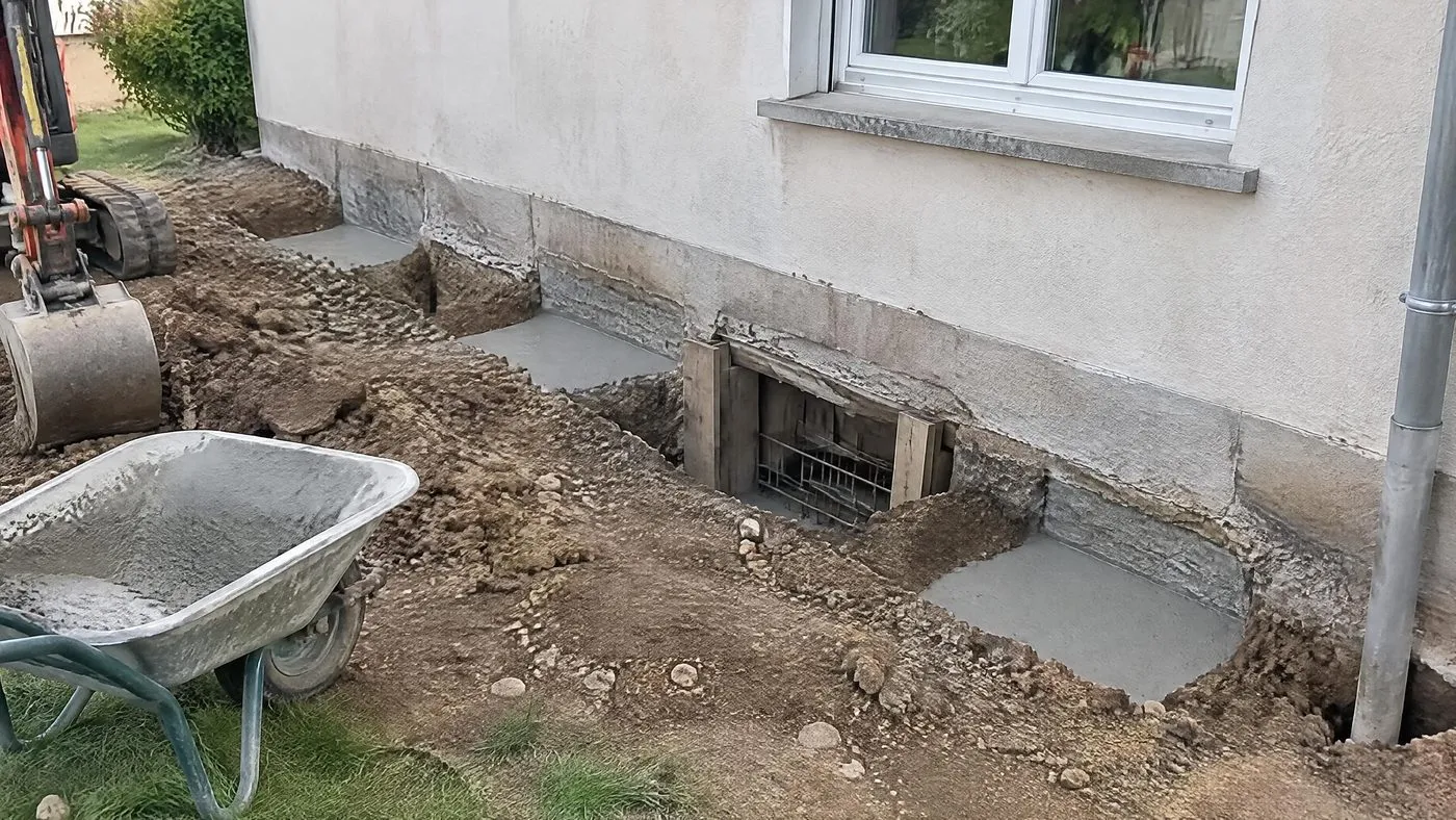 Reprise de fondation par passes alternées au pied d'un mur enduit : tronçons coulés et tronçons encore en terre