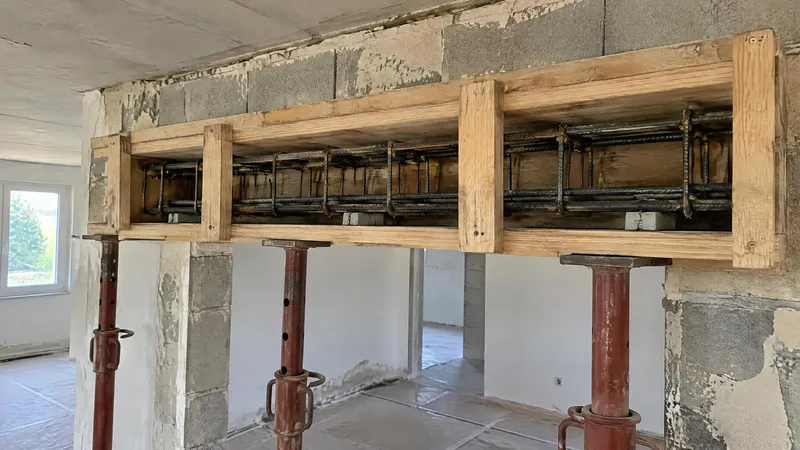 Coffrage bois d'un linteau béton armé au-dessus d'une future ouverture, ferraillage visible, étais en place