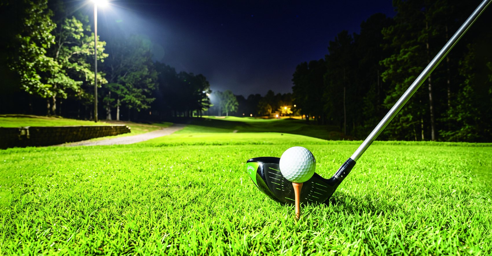 Golf ball on tee under LED lights at night