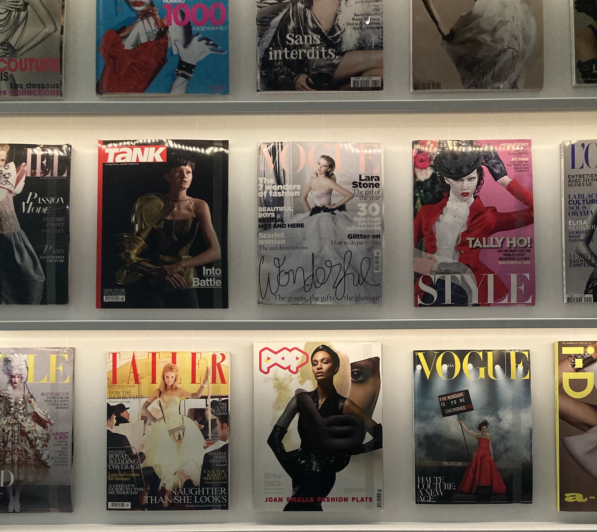 Rows of fashion magazine covers displayed on a lit wall
