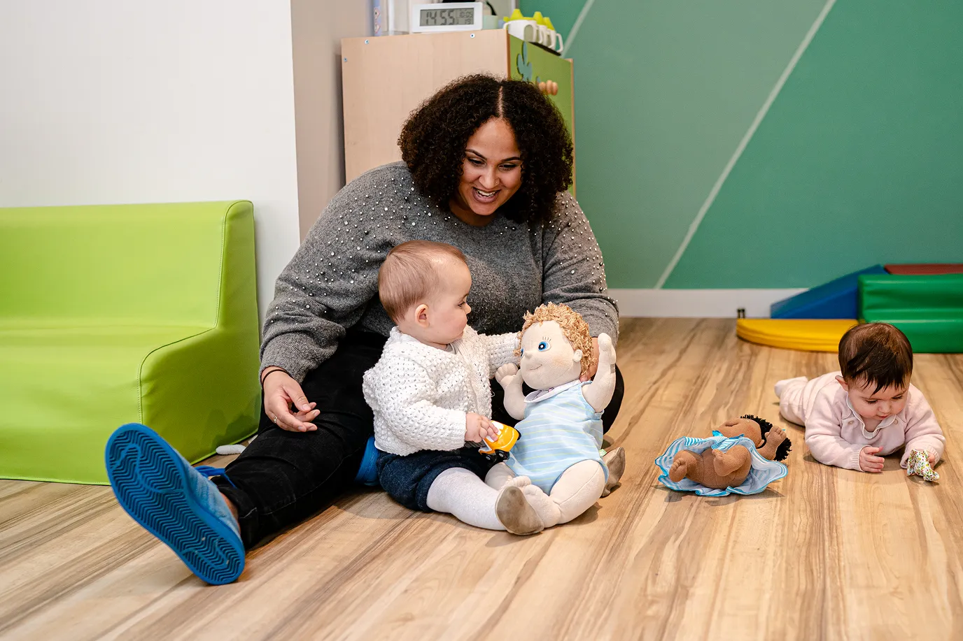 Une professionnelle joue au sol avec deux bébés