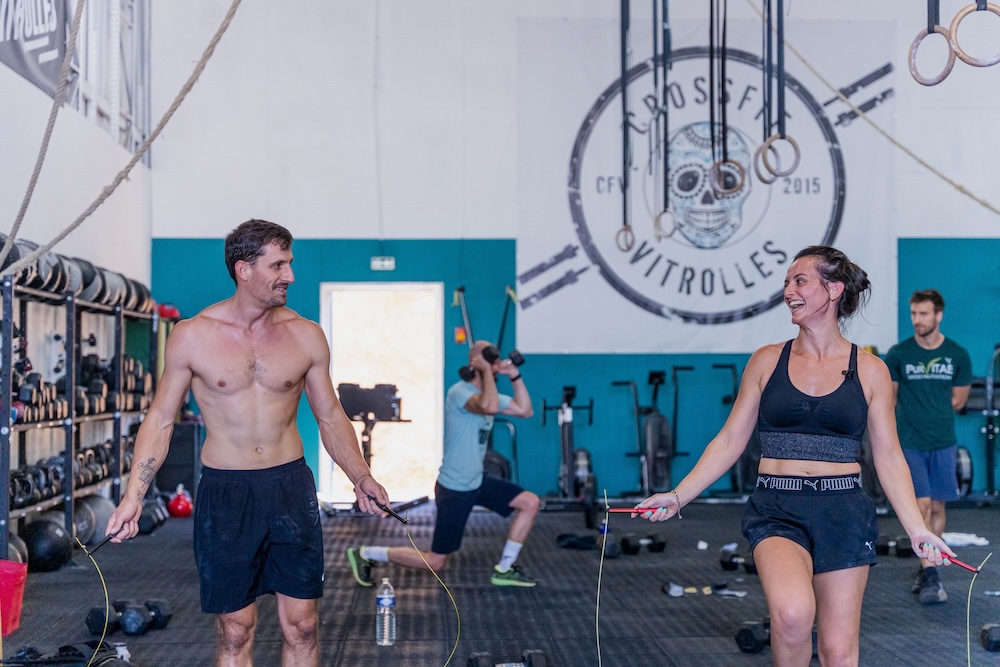 Caro et Antho à la corde à sauter dans la box CrossFit Vitrolles, logo de la box au mur