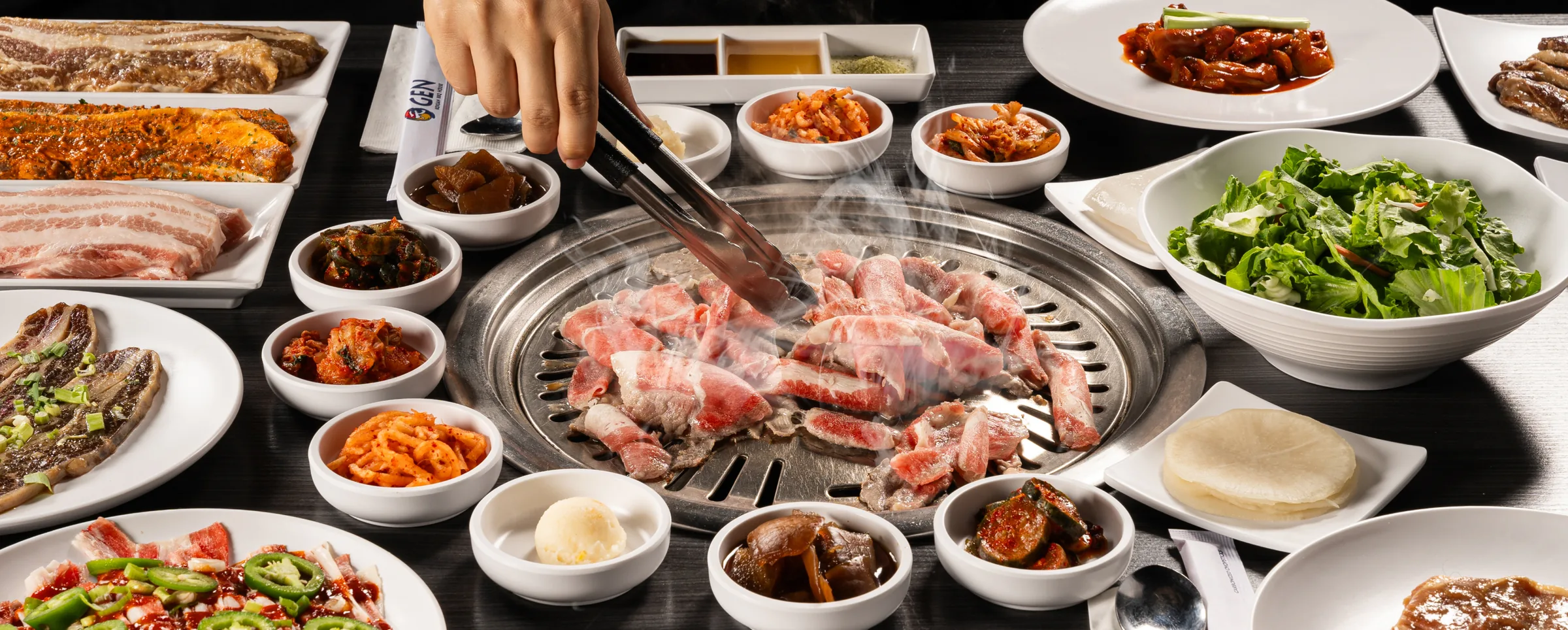 A GEN table spread with meat on the grill and banchan